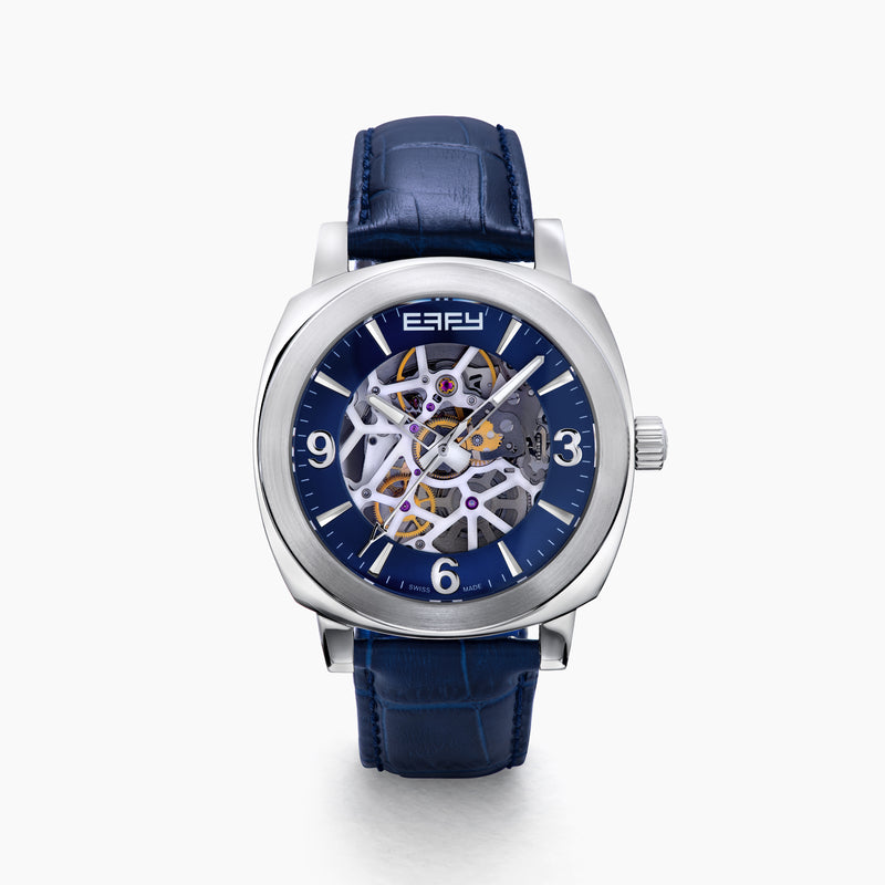 The 41MM Swiss Made Stainless Steel and Leather Automatic Skeleton Watch features a silver case, blue leather strap and bezel, a skeleton dial with visible gears, white hour markers and hands, plus the ERIFY brand name at the top.
