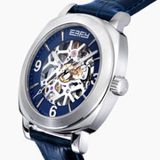 The 41MM Swiss Made Stainless Steel and Leather Automatic Skeleton Watch features a silver case, blue leather strap and bezel, a skeleton dial with visible gears, white hour markers and hands, plus the ERIFY brand name at the top.