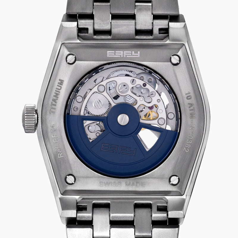 A 42MM Swiss made titanium automatic skeleton watch featuring a geometric bezel that reveals intricate gears and movements beneath the dial, complemented by a metal link bracelet.