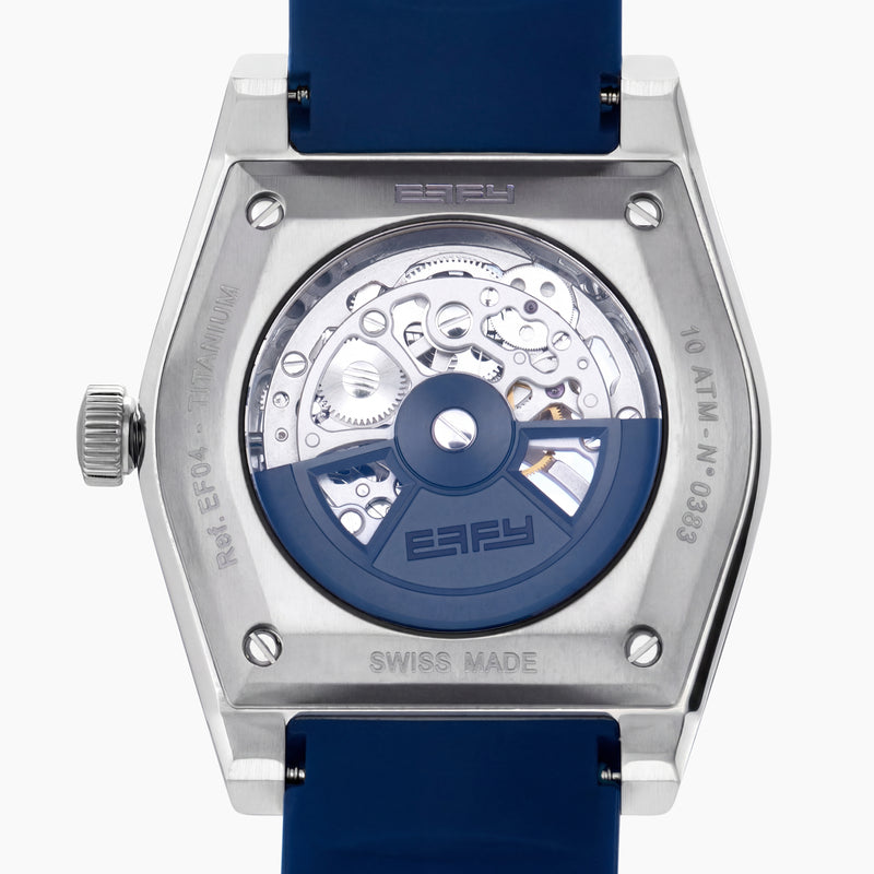 Introducing the 42MM Swiss Made Titanium and Silicone Automatic Skeleton Watch—a luxurious timepiece featuring a geometric silver titanium case and exposed inner mechanisms. Accented with a blue bezel and paired with a blue silicone strap, this design stands out against a white backdrop. Its exceptional clarity and elegance are enhanced by a diamond-cut sapphire crystal.