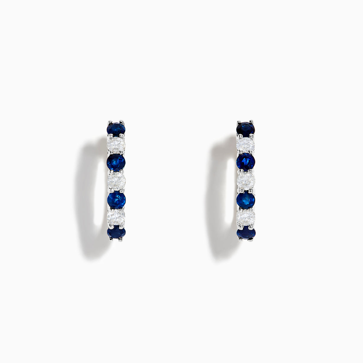 The 14K White Gold Blue Sapphire & Diamond Hoop Earrings, 1.10 TCW, are shown on a plain white background with soft left-side shadows, highlighting alternating sapphire and diamond stones.