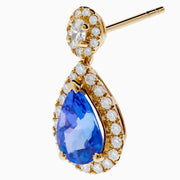 The Nahla 14K Yellow Gold Tanzanite and Diamond Drop Earrings feature teardrop-shaped blue tanzanite gems encircled by white diamonds, with extra diamonds set in the round studs, shown against a white background.