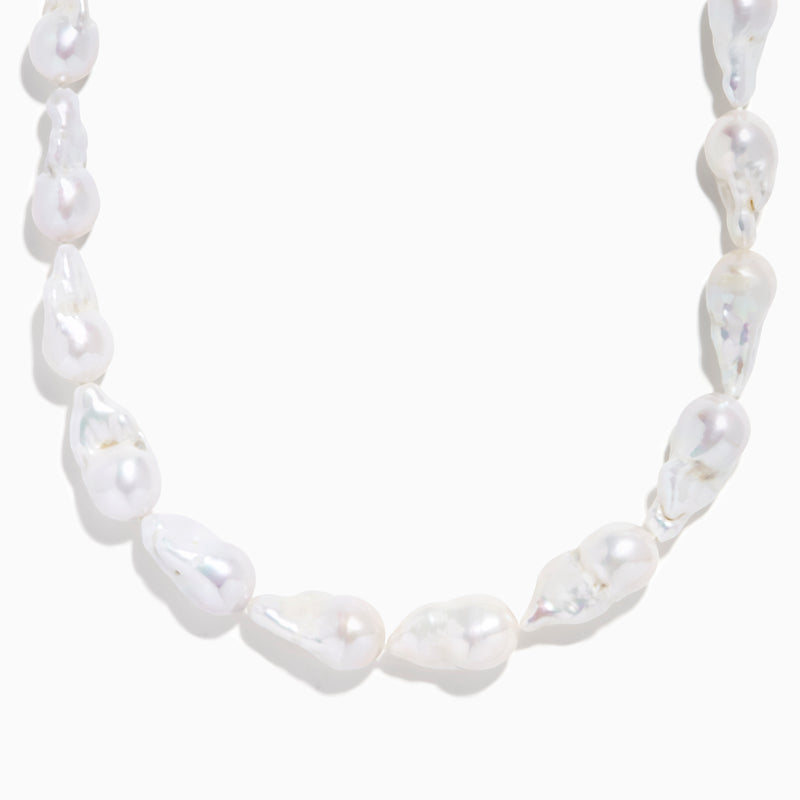 A close-up of the 14K Yellow Gold Freshwater Baroque Pearl Necklace featuring irregularly shaped white pearls and a 14K yellow gold clasp, set against a white background.