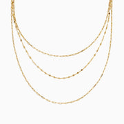The 14K Yellow Gold Layered Chain Necklace features three delicate chains of different lengths with evenly spaced links, displayed on a white background—a perfect set for achieving effortless elegance.