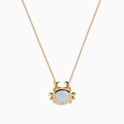 The Seaside 14K Yellow Gold Mother Of Pearl and Diamond Crab Necklace features a white oval mother of pearl center, shimmering diamond accents, and a charming crab pendant on a delicate yellow gold chain.