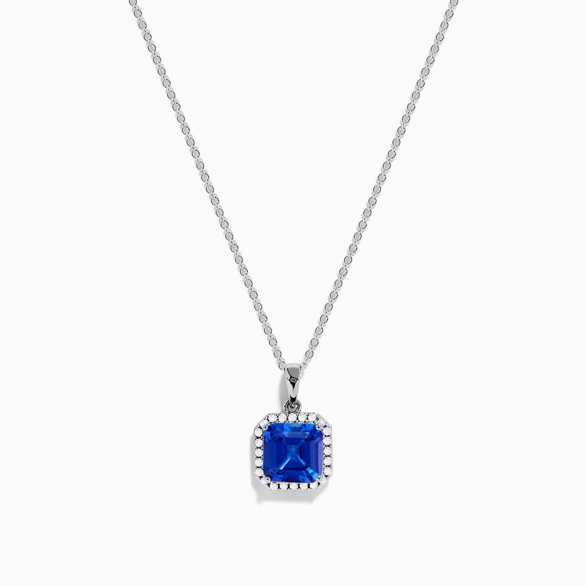 The Nahla Siri 14K Gold Tanzanite and Diamond Pendant features a square blue tanzanite gemstone surrounded by sparkling diamonds, displayed against a white background.