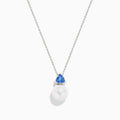 The Nahla 14K White Gold Fresh Water Pearl and Tanzanite Pendant features a round pearl accented with a small, triangular blue tanzanite, all set in white gold and shown against a plain white background.