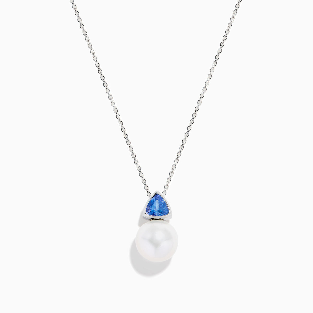 The Nahla 14K White Gold Fresh Water Pearl and Tanzanite Pendant features a round pearl accented with a small, triangular blue tanzanite, all set in white gold and shown against a plain white background.