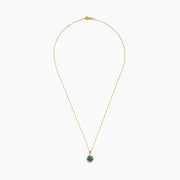 The 14K Yellow Gold Blue Diamond Cushion Pendant features a hexagonal pendant with a deep blue gemstone, set on a yellow gold chain and displayed against a white background.