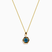 The 14K Yellow Gold Blue Diamond Cushion Pendant features a hexagonal pendant with a deep blue gemstone, set on a yellow gold chain and displayed against a white background.