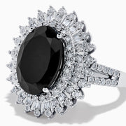 The 14K White Gold Onyx and Diamond Double Halo Ring features a large oval onyx surrounded by two rows of sparkling white diamonds, set on a white gold band and displayed against a white background.