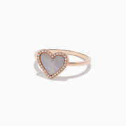 The 14K Rose Gold Mother of Pearl and Diamond Heart Ring features a heart-shaped mother-of-pearl centerpiece framed by sparkling diamonds.