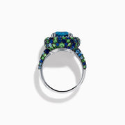 The 925 Sterling Silver Blue Topaz Cushion Multi Gemstone Halo Ring features a large rectangular blue topaz center, encircled by a halo of small white, green, and blue stones.
