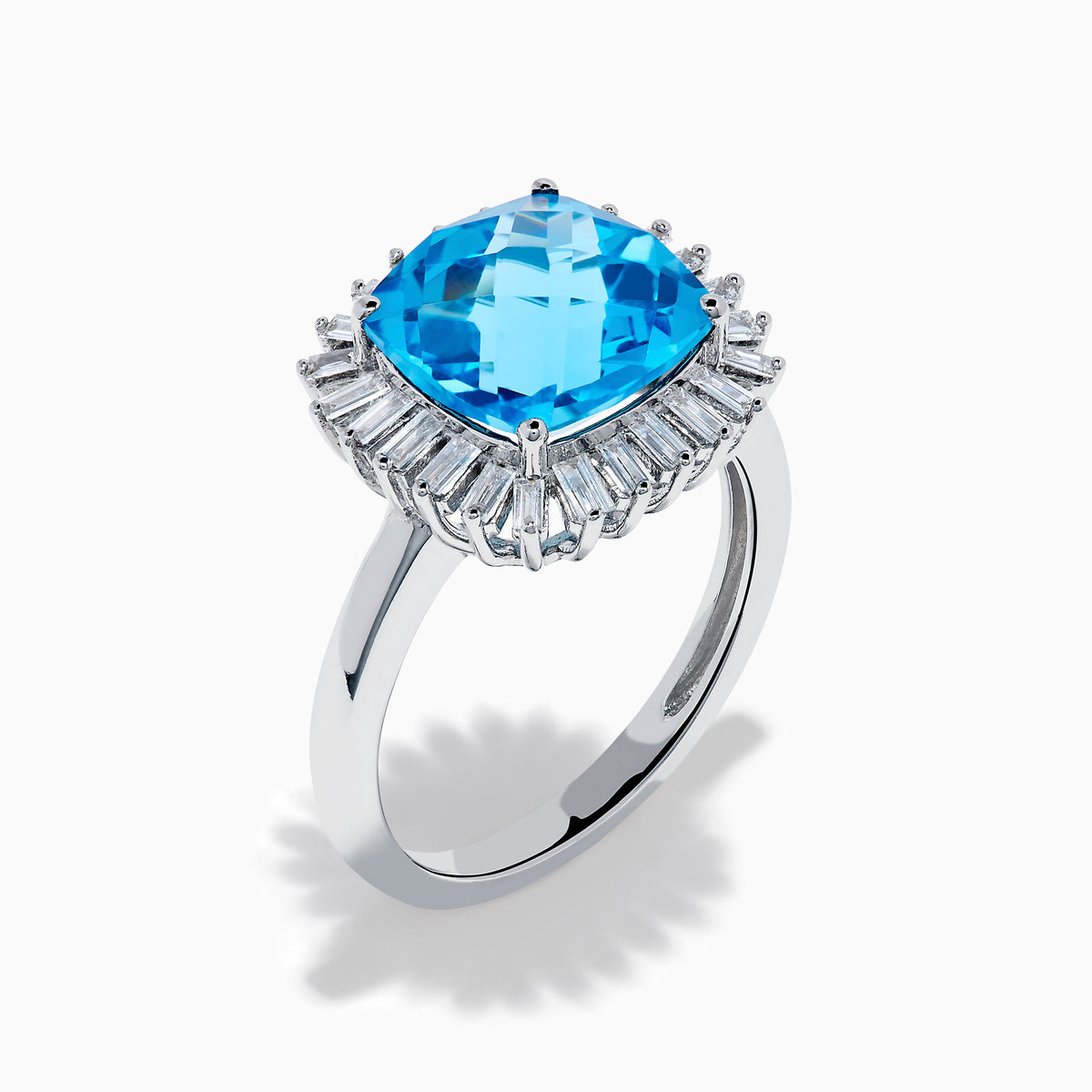 The Ocean Bleu 14K White Gold Blue Topaz and Diamond Halo Ring features a large cushion-cut blue topaz center stone, surrounded by a sparkling halo of baguette-shaped diamonds, all set in elegant white gold.