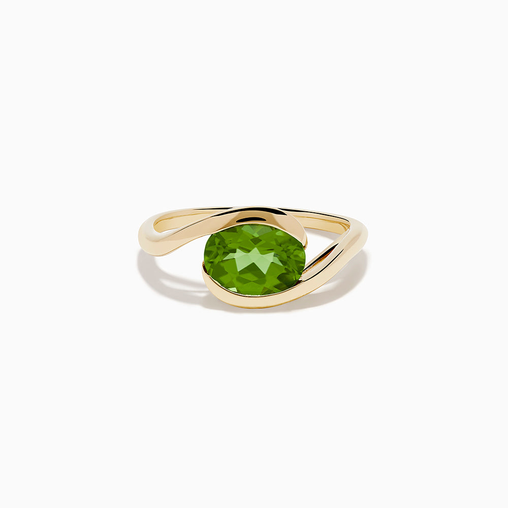 The 14K Yellow Gold Bypass Peridot Ring features a large round faceted green peridot centered on an elegant modern twisting band.