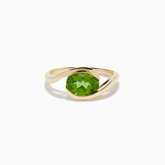 The 14K Yellow Gold Bypass Peridot Ring features a large round faceted green peridot centered on an elegant modern twisting band.