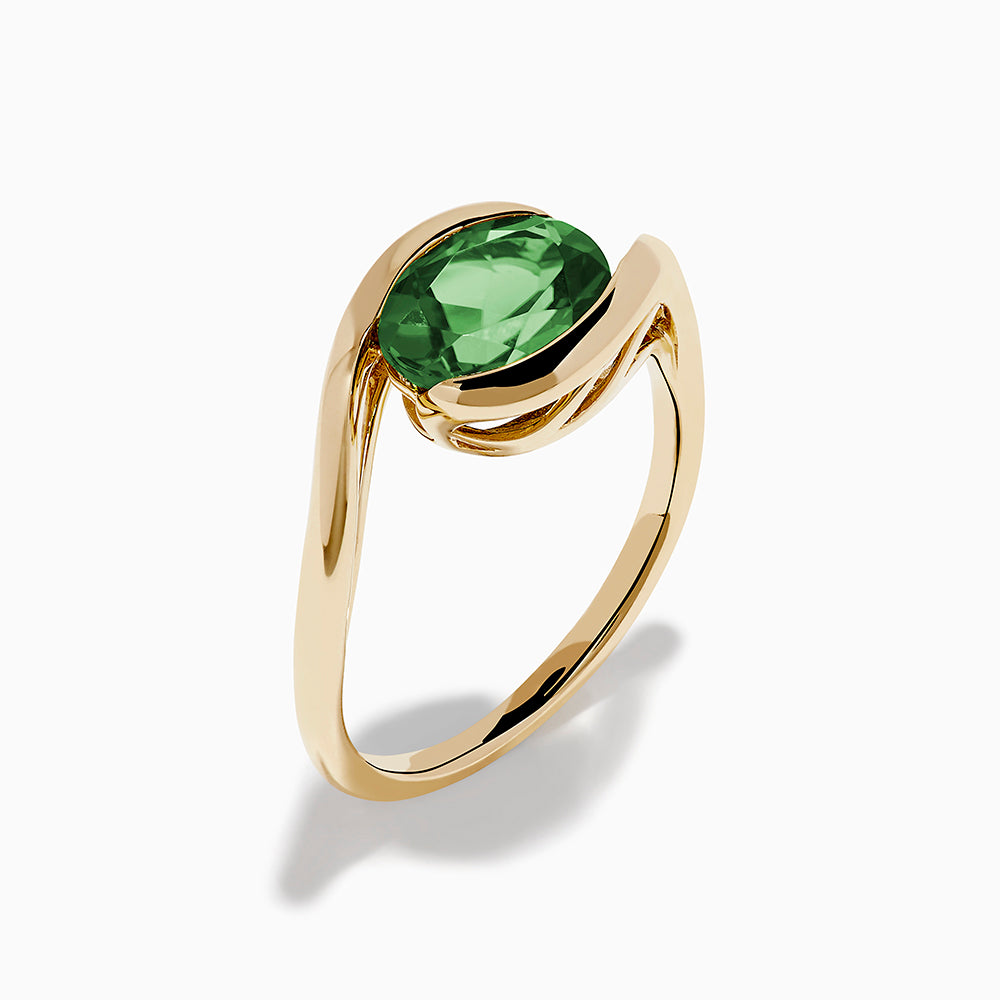 The 14K Yellow Gold Bypass Peridot Ring features a large round faceted green peridot centered on an elegant modern twisting band.