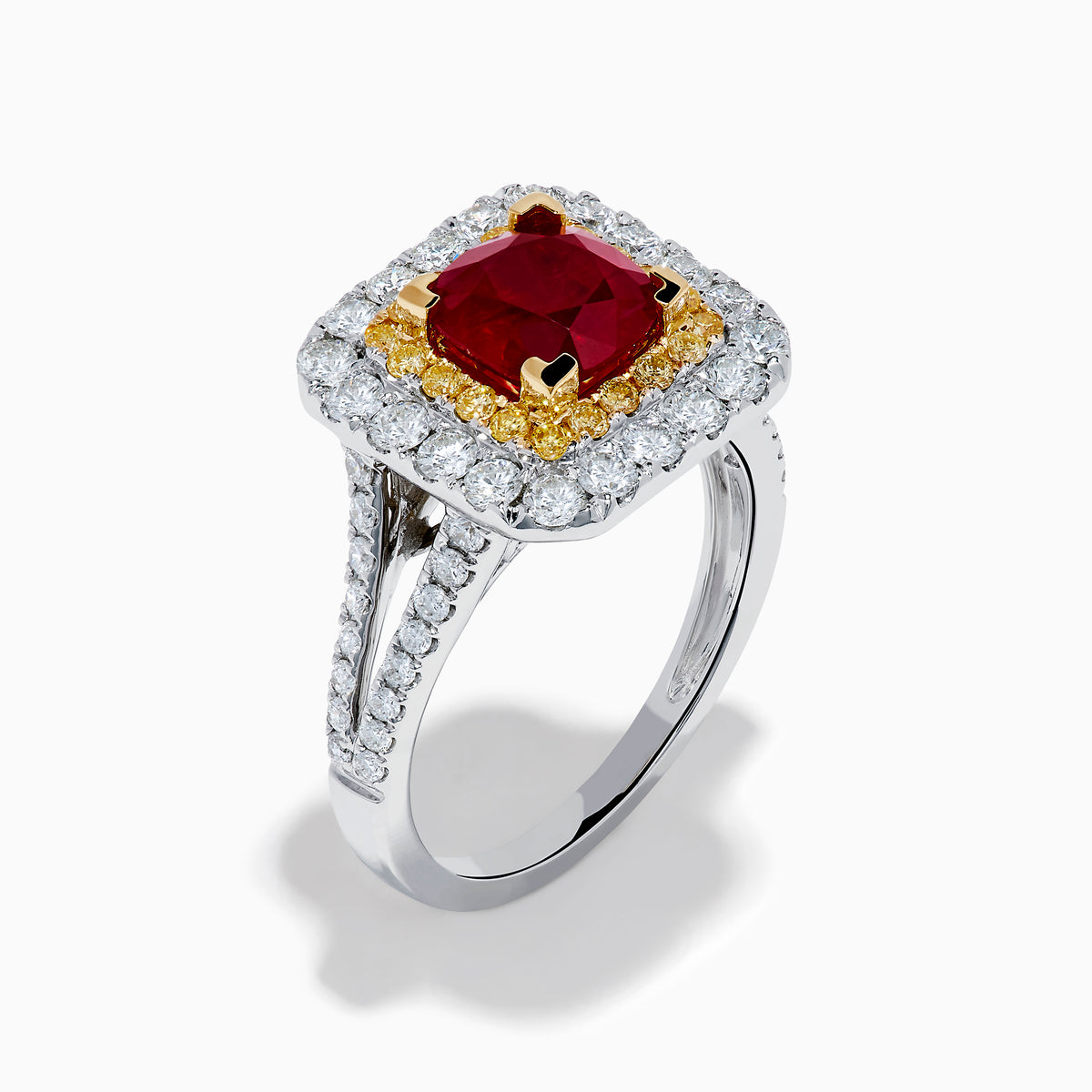 The 18K 2-Tone Gold Ruby, Yellow and White Diamond Double Halo Ring features a square ruby center, surrounded by yellow and white diamonds, set on a silver band with diamond accents.
