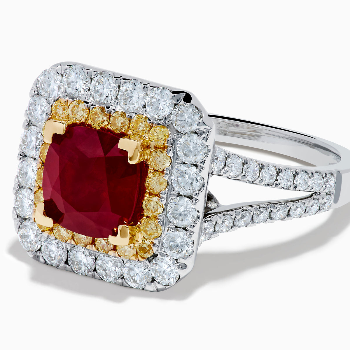 The 18K 2-Tone Gold Ruby, Yellow and White Diamond Double Halo Ring features a square ruby center, surrounded by yellow and white diamonds, set on a silver band with diamond accents.