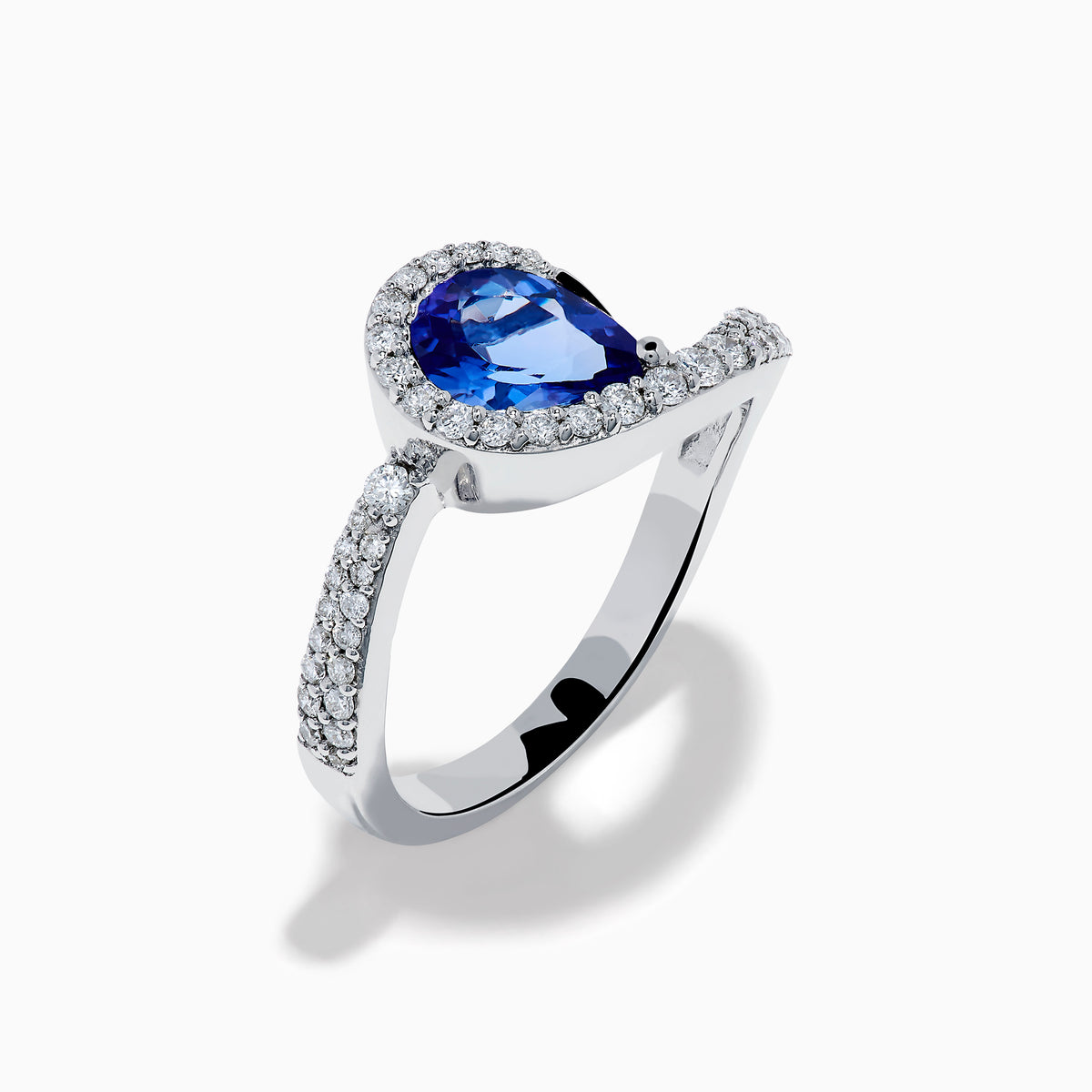 The Nahla 14K White Gold Tanzanite and Diamond Pear Swirl Ring showcases a pear-shaped blue tanzanite center, haloed by diamonds and accented with diamonds along a sweeping band.