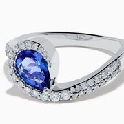 The Nahla 14K White Gold Tanzanite and Diamond Pear Swirl Ring showcases a pear-shaped blue tanzanite center, haloed by diamonds and accented with diamonds along a sweeping band.