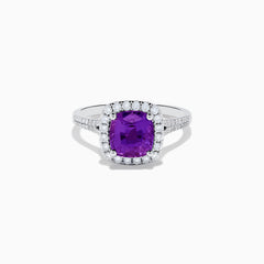 The 18K White Gold Purple Sapphire and Diamond Halo Ring showcases a cushion-cut purple sapphire center, encircled by a diamond halo and diamonds along the band.