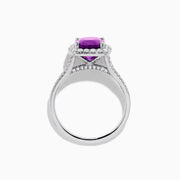 The 18K White Gold Purple Sapphire and Diamond Halo Ring showcases a cushion-cut purple sapphire center, encircled by a diamond halo and diamonds along the band.