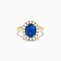 The Royale Bleu 18K Yellow Gold Blue Sapphire and Diamond Halo Ring showcases a striking oval blue sapphire centerpiece surrounded by a sparkling diamond halo.
