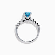 The Lab Grown Blue and White Diamond Ring set in 14K White Gold features a large round blue and white diamond at the center, accented by smaller clear stones, displayed against a white background.