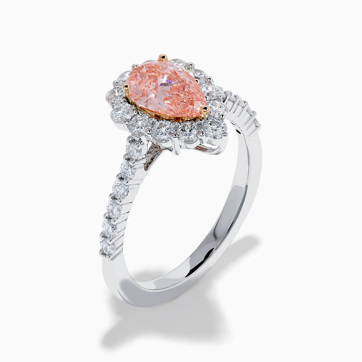 The Lab Grown Pink and White Diamond Halo Ring in 14K Two Tone Gold features a pear-shaped pink center, a halo of white diamonds, and a diamond-studded band, shown on a white background.