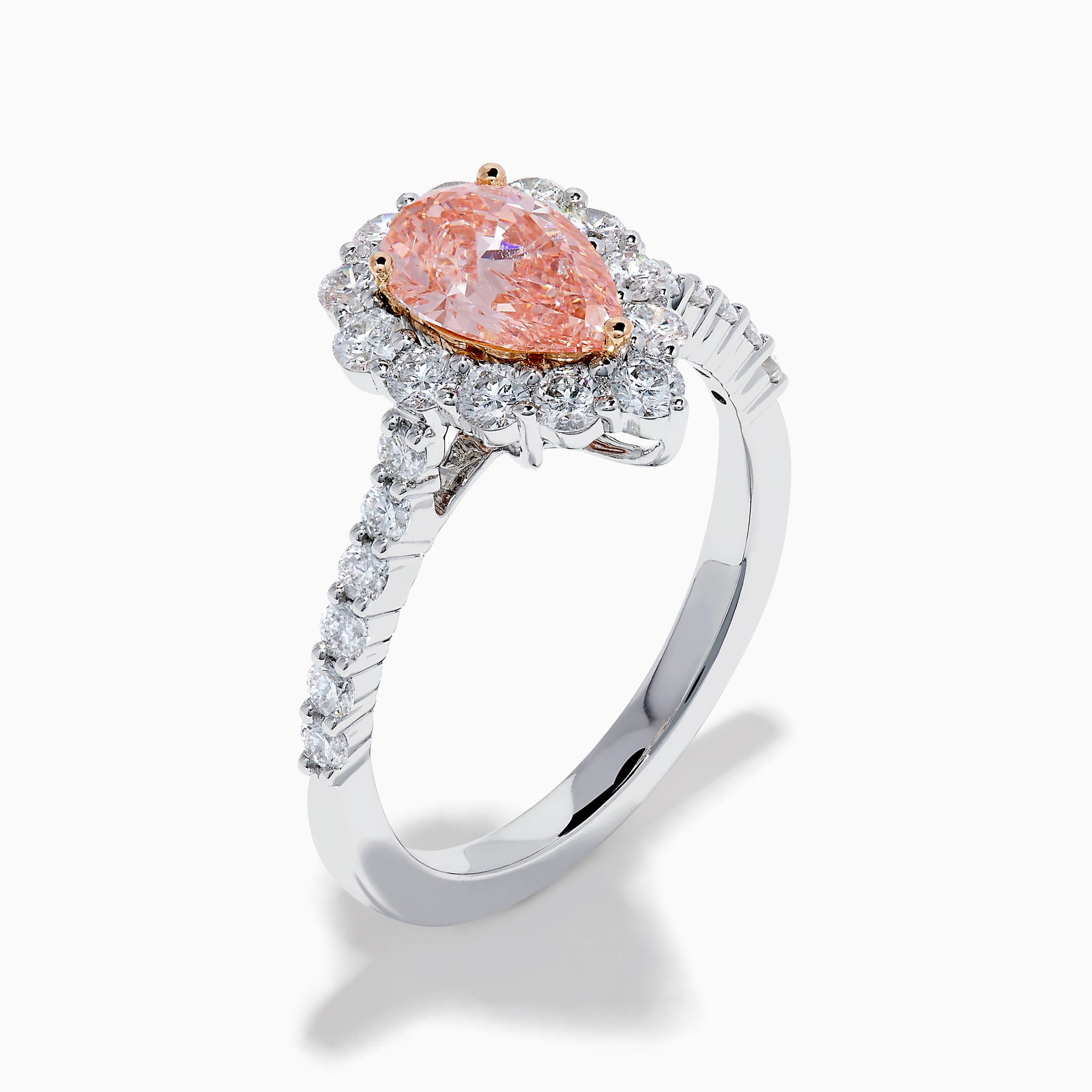 The Lab Grown Pink and White Diamond Halo Ring in 14K Two Tone Gold features a pear-shaped pink center, a halo of white diamonds, and a diamond-studded band, shown on a white background.