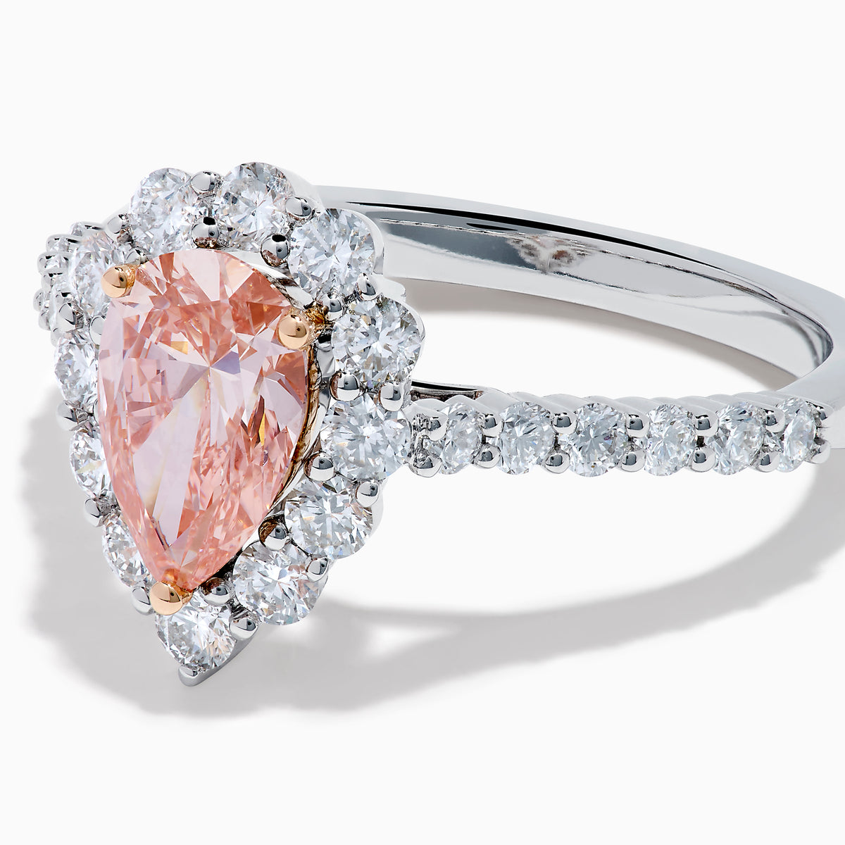 The Lab Grown Pink and White Diamond Halo Ring in 14K Two Tone Gold features a pear-shaped pink center, a halo of white diamonds, and a diamond-studded band, shown on a white background.