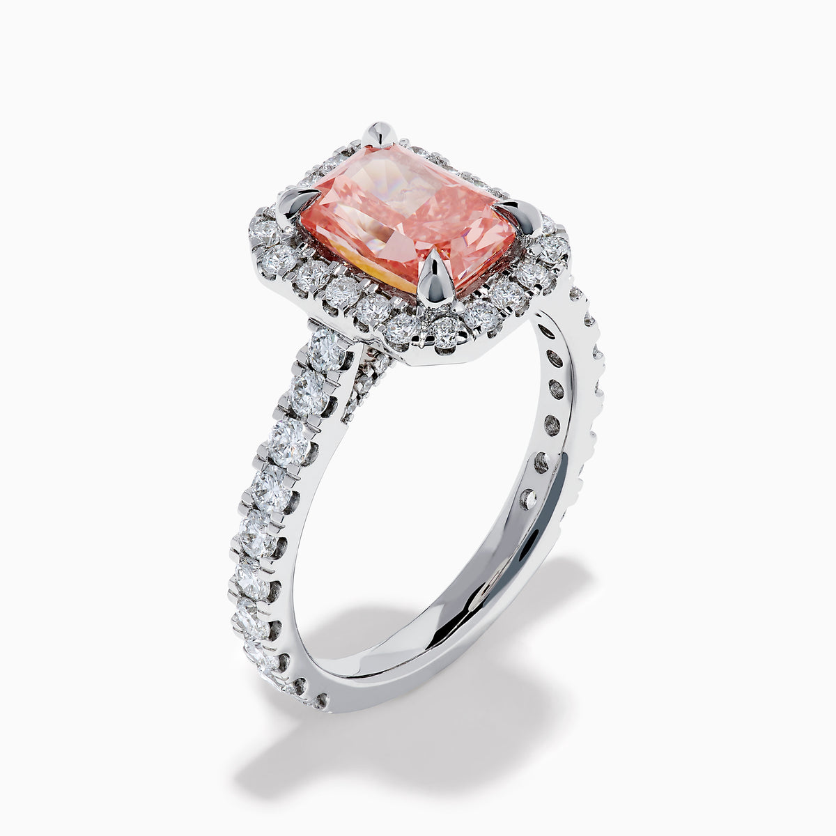 The Lab Grown Pink and White Diamond Halo Ring in 14K White Gold features a rectangular pink gemstone, a halo of lab grown diamonds, and a diamond-studded band, elegantly showcased on a white background.