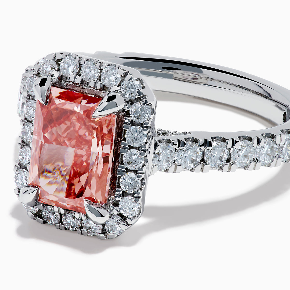 The Lab Grown Pink and White Diamond Halo Ring in 14K White Gold features a rectangular pink gemstone, a halo of lab grown diamonds, and a diamond-studded band, elegantly showcased on a white background.