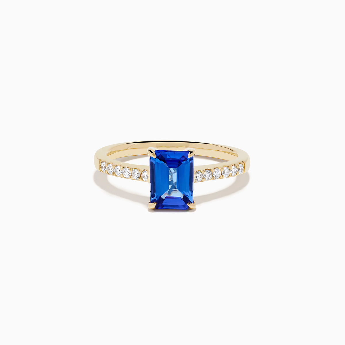 The Nahla 14K Yellow Gold Tanzanite and Diamond Ring showcases a rectangular blue tanzanite center stone, accented by small round white diamonds along the upper band on a plain white background—timeless elegance in every detail.