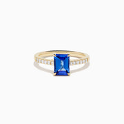 The Nahla 14K Yellow Gold Tanzanite and Diamond Ring showcases a rectangular blue tanzanite center stone, accented by small round white diamonds along the upper band on a plain white background—timeless elegance in every detail.