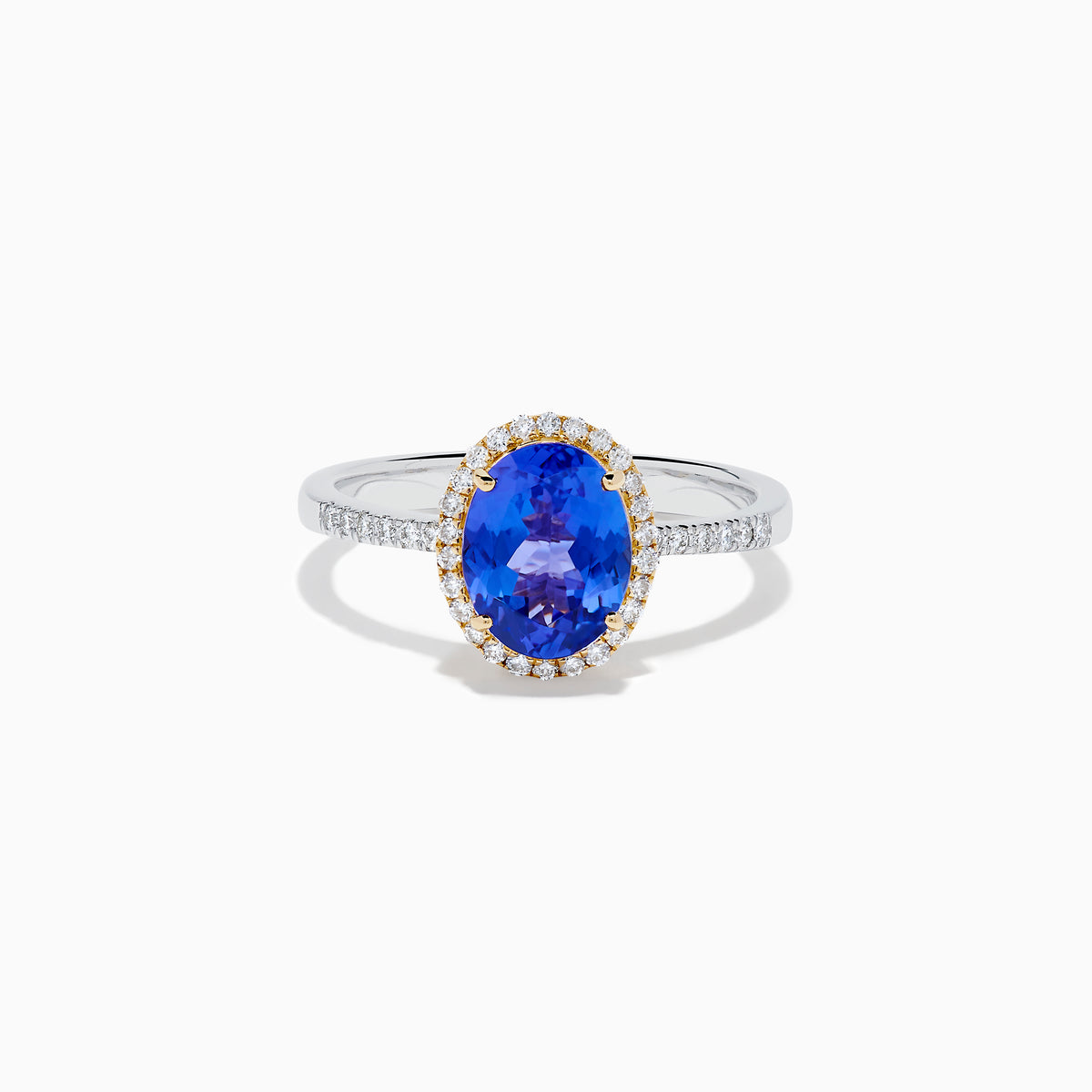 The Nahla 14K Two Tone Gold Tanzanite and Diamond Halo Ring features an oval blue tanzanite center, encircled by a diamond halo and diamond-accented band, all set in elegant two-tone 14K gold.