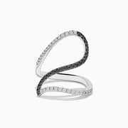 The 14K White Gold Black and White Diamond Fashion Ring features an open, wavy design with intertwined bands of sparkling white and black diamonds, creating a modern and elegant look.
