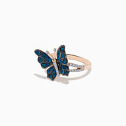 The Bella Bleu 14K Rose Gold White and Blue Diamond Butterfly Ring features blue diamonds on the wings, clear stones on the body, and a mix of rose gold and silver tones, elegantly displayed on a white background.