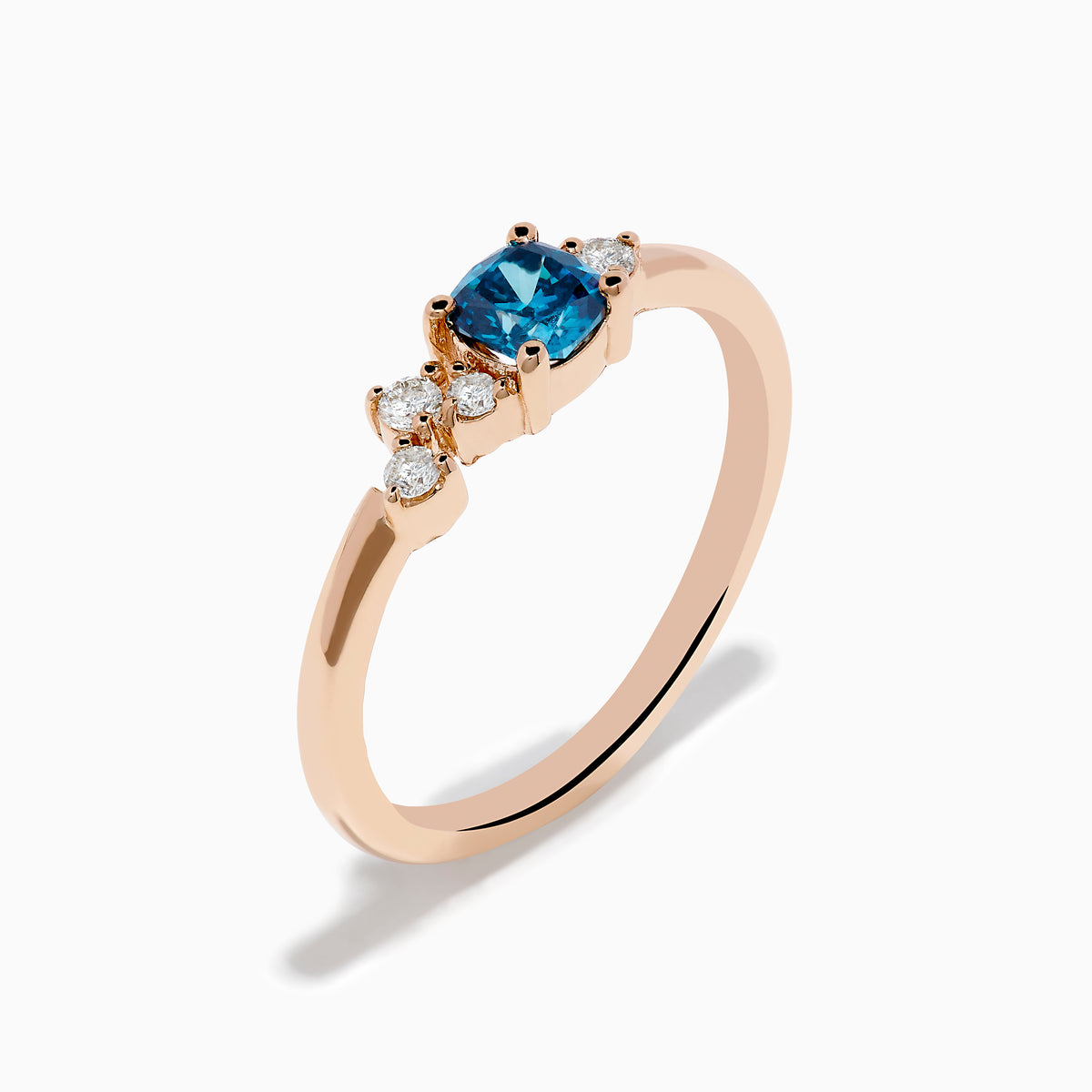 The 14K Rose Gold Blue and White Diamond Ring features a square-cut blue gemstone at the center with small round white diamonds on one side, displayed on a plain white background.