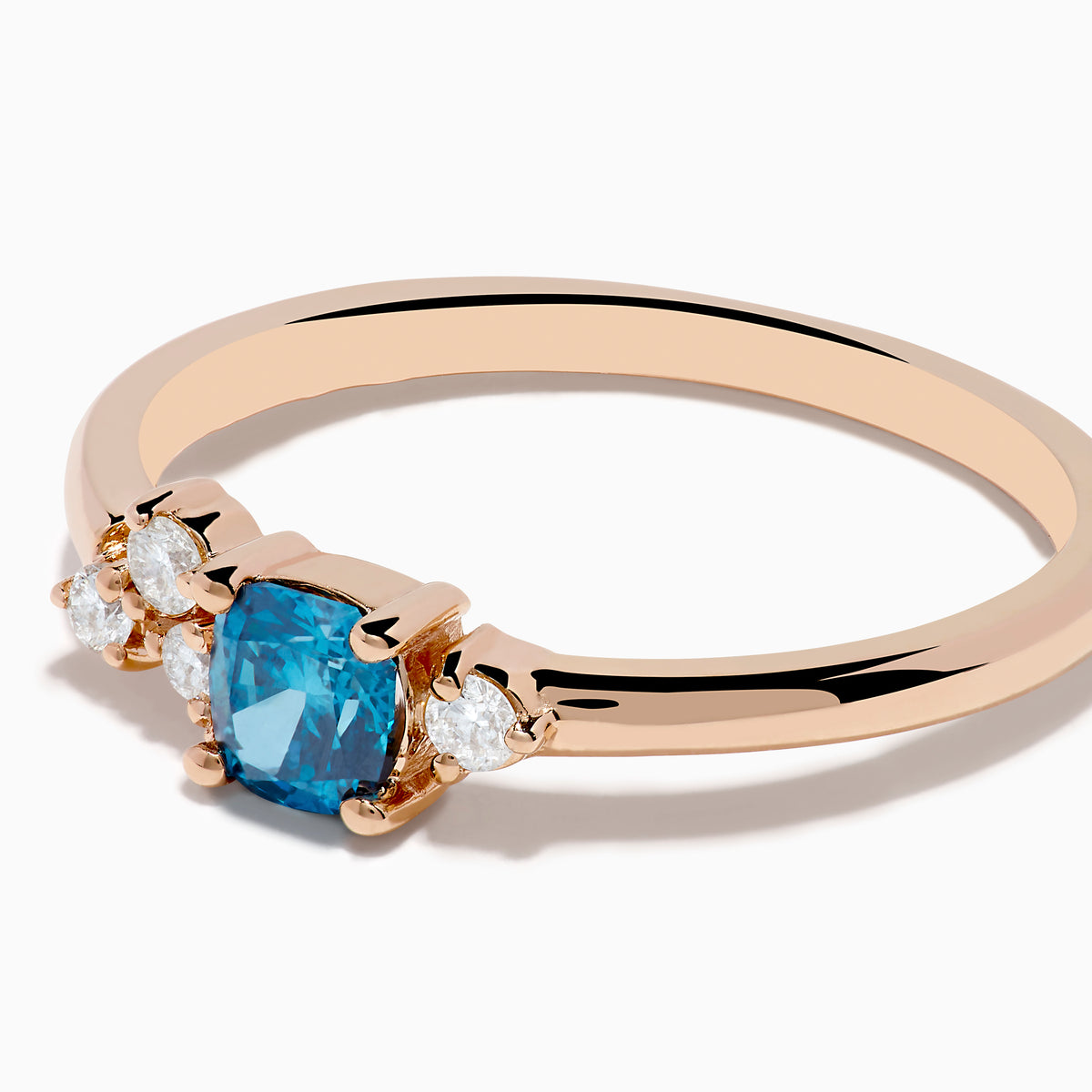 The 14K Rose Gold Blue and White Diamond Ring features a square-cut blue gemstone at the center with small round white diamonds on one side, displayed on a plain white background.