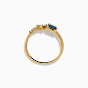 The 14K Yellow Gold Blue and White Diamond Ring features a square blue diamond, a smaller square white diamond, and three round white stones set asymmetrically on a plain band.