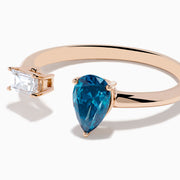 The 14K Rose Gold Blue and White Diamond Toi Et Moi Ring features an open design with a clear rectangular diamond and a blue teardrop diamond, elegantly displayed on a white background.