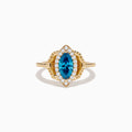 The 14K Yellow Gold Blue and White Diamond Marquise Ring features a striking blue and white diamond centerpiece, accented by a halo of round white diamonds and detailed band craftsmanship.
