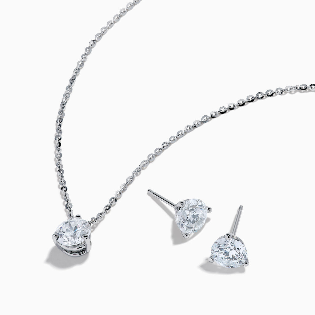 The Lab Grown Diamond Earring and Necklace Set in 14K White Gold features a heart-shaped diamond pendant on a silver necklace and matching heart-shaped diamond stud earrings, all showcased on a white background.