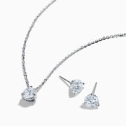 The Lab Grown Diamond Earring and Necklace Set in 14K White Gold features a heart-shaped diamond pendant on a silver necklace and matching heart-shaped diamond stud earrings, all showcased on a white background.