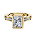 The 18K Yellow Gold Bezel Full Bezel North/South Classic Flat 1-Row-Pave 2.5mm Engagement Ring features a large radiant-cut center stone in a gold bezel, with small round diamonds set along both sides of the band.