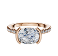 A 14K rose gold engagement ring featuring a half bezel east/west cathedral dome setting with a central stone and a 1-row pave of smaller diamonds along the 2.5mm band.
