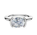 A 14K white gold bezel half bezel east/west classic dome 2.0mm engagement ring is shown with a large, round diamond set in a modern cushion-shaped setting against a plain white background.
