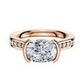 The 18K Rose Gold Bezel Half Bezel East/West Cathedral Flat 1-Row-Pave 2.5mm Engagement Ring features an oval center diamond in a bezel setting with small round pave diamonds along the band, displayed on a white background.